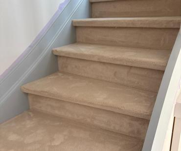 Escalier droit rénové avec un tapis beige à Wavre